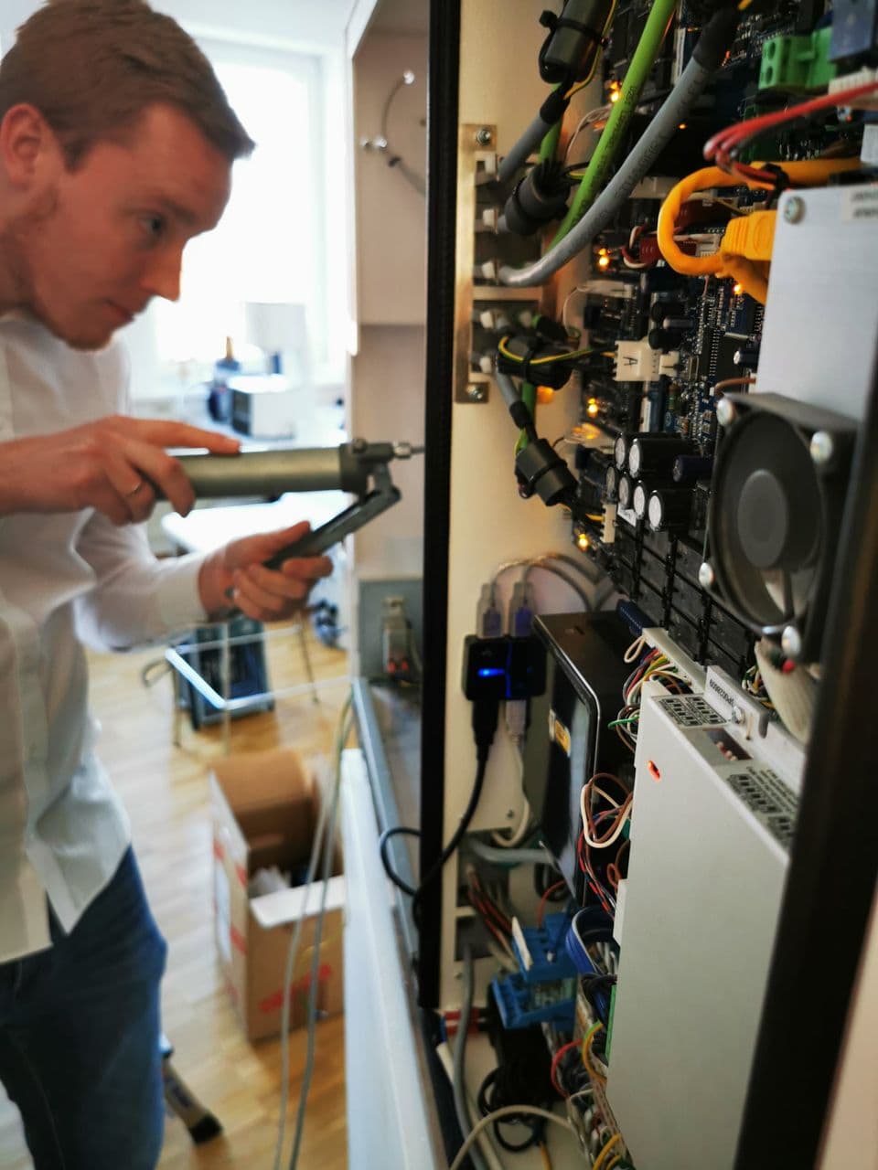 Techniker arbeitet an einem geöffneten Elektronikbereich einer Fräsmaschine